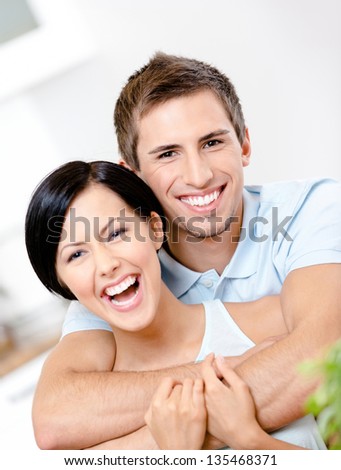 Man embraces his smiley girlfriend in the kitchen
