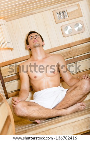 Half-naked girl relaxing in asana position in sauna. Concept of self-care, health and relaxation