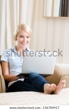 Woman sitting on the couch with silver computer. Concept of education and online communication