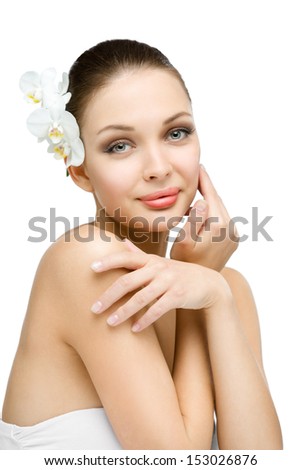 Naked girl with orchid in hair touches her face, isolated on white. Concept of natural beauty and youth