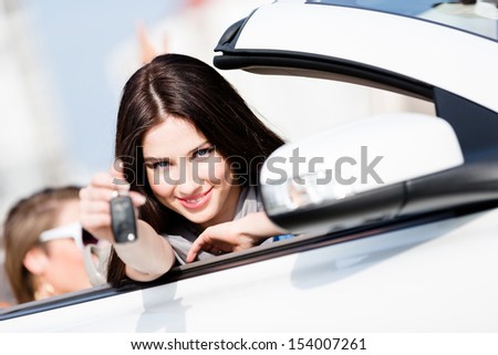 Girl in the car shows car key. Buying car and getting the freedom