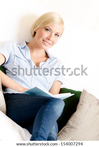 Female sitting on the sofa reads a book. Concept of education and useful pastime