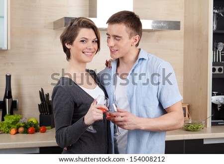 Couple with goblets embraces one another in the modern comfortable kitchen