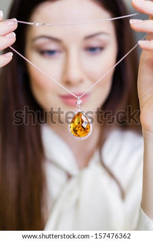 Girl holding necklace with yellow sapphire at jeweler\'s shop. Concept of wealth and luxurious life