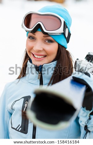 Portrait of female wearing sports jacket and goggles who hands skis