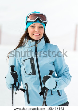 Half-length portrait of female who goes skiing and wears goggles and sports jacket for winter sports