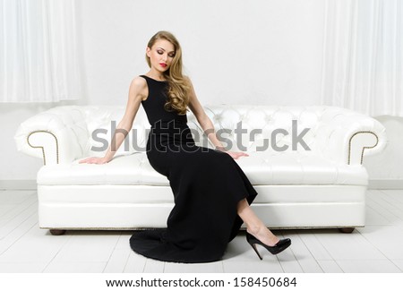 Woman sitting on white leather sofa. Concept of beauty and perfection