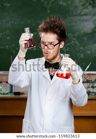 Mad professor wonders at the flasks with colored liquid