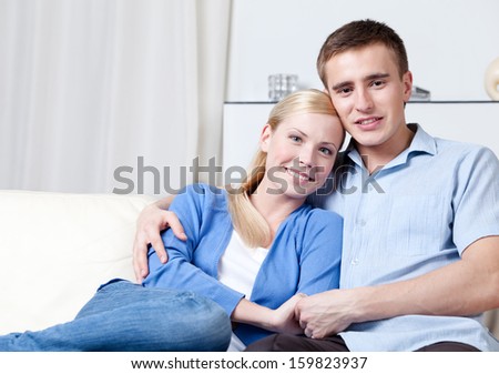 Man and woman embrace each other sitting on the white leather sofa