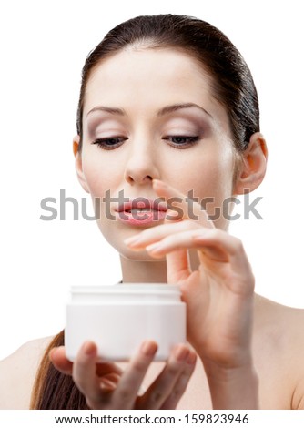 Woman holding cream container and starting to apply face cream, isolated on white