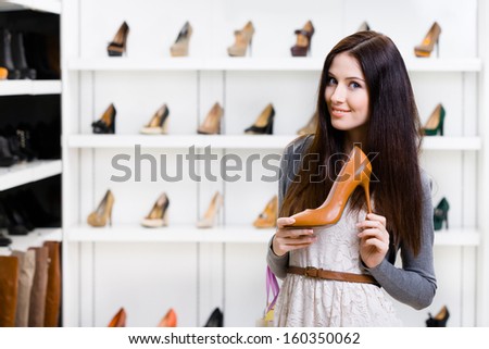 Half-length portrait of woman keeping brown leather high heeled shoe in shopping center