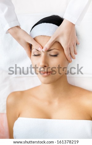 Portrait of half-naked lady with closed eyes getting face massage. Concept of relax and medicine