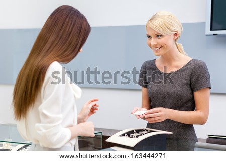 Consultant helps lady to choose jewelry at jeweler\'s shop. Concept of wealth and luxurious life