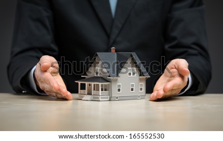 Close up of hands with little home. Concept of deal and realty