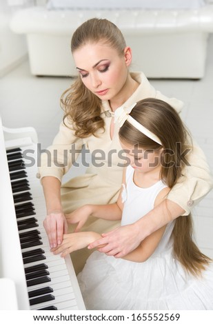 Tutor teaches little girl to play piano. Concept of music study and leisure