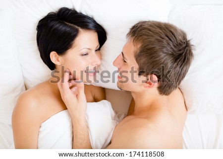 Close up of man stroking woman lying in bed, top view. Concept of love and affection