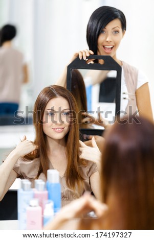 Hair stylist showing the ready haircut of the female client in mirror. Concept of fashion and beauty