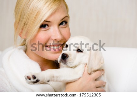 Woman in white sweater holds a cute Labrador puppy