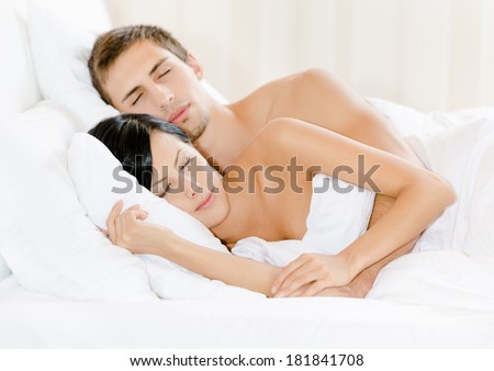 Couple sleeping in bed under white eiderdown