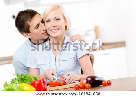 Man kisses female while she is cooking sitting at the kitchen table full of groceries
