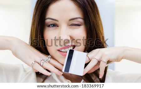 Girl with lots of rings on hands keeps credit card. Concept of wealth and luxurious life