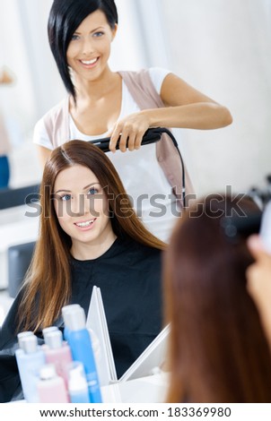 Reflection of hairdresser doing hair style for woman in hairdress salon. Concept of fashion and beauty