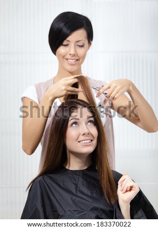 Hair stylist cuts hair of woman in hairdressing salon. Concept of fashion and beauty