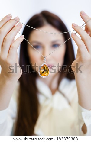 Woman holding necklace with yellow sapphire at jeweler\'s shop. Concept of wealth and luxurious life