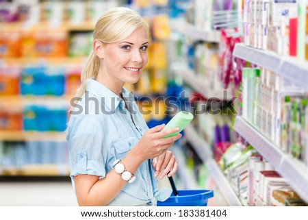 Half length portrait of girl at the shop choosing cosmetics among the great variety of products. Concept of consumerism, retail and purchase