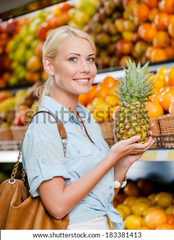 Girl at the shop choosing fruits and vegetables hands pineapple