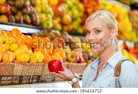 Girl at the shop choosing fruits and vegetables hands fresh red apple