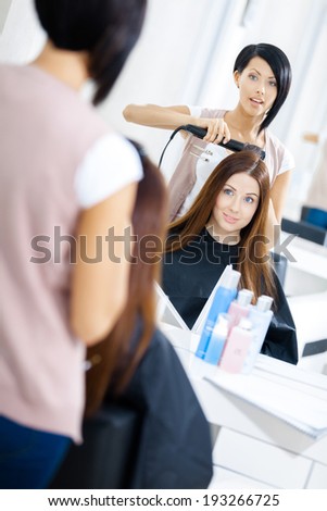 Reflection of hairdresser doing haircut for woman in hairdress salon. Concept of fashion and beauty