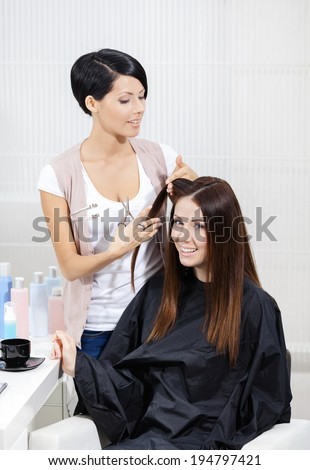 Beautician cuts hair of woman in hairdressing salon. Concept of fashion and beauty