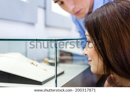 Girl with man selects expensive jewelry at jeweler\'s shop. Concept of wealth and luxurious life