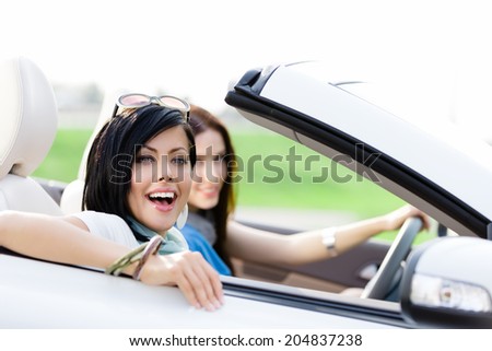 Two happy friends in the convertible car driving everywhere and looking for freedom and fun