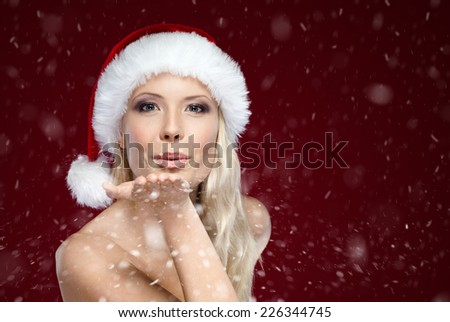 Beautiful woman in Christmas cap blows kiss, isolated on purple