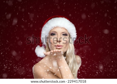 Beautiful woman in Christmas cap blows kiss, isolated on purple