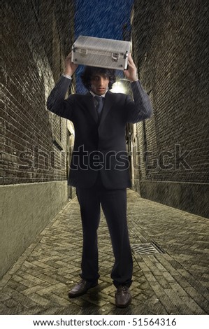 Businessman walking in an alley in the rain