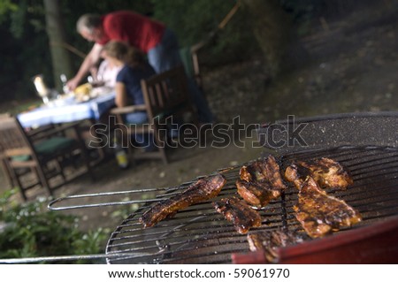 BBq with meat in foreground people in background