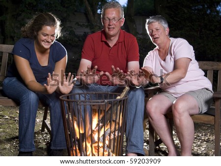 Family at campfire in the garden warming their hands