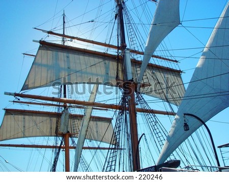 A SHIPS SAILS AND MAST WITH HIGH SUN.
