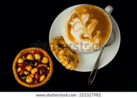 cup of cappucino and cakes on black background