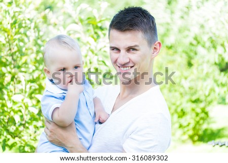 charming caucasian baby boy with father in garden high key