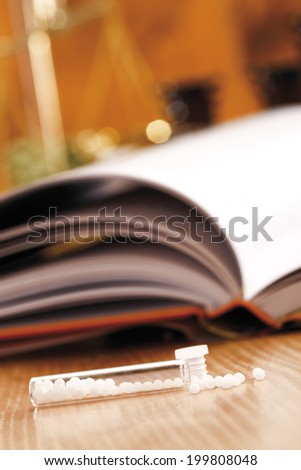 Homeopathic remedy in front of homeopathic book, close-up