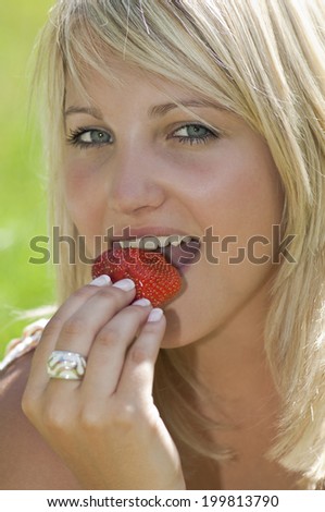 Austria, Salzburger Land, Altenmarkt, Young woman eating strawberry, portrait