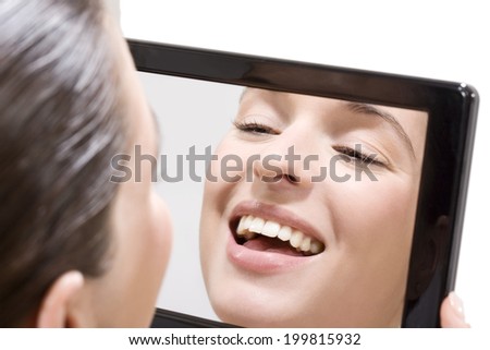Young woman looking into mirror, smiling, portrait