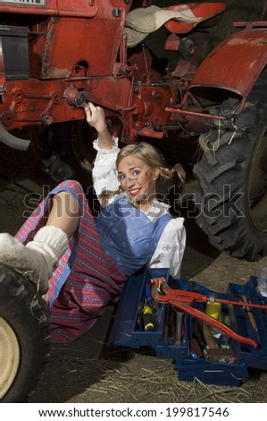 Young woman repairing tractor, portrait