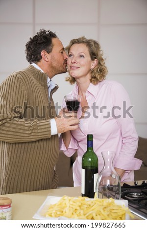 Couple drinking wine, man kissing woman on the cheek