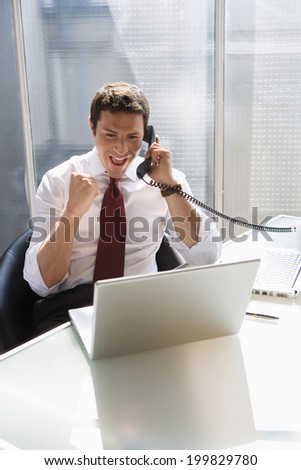 Young man sitting in office using telephone