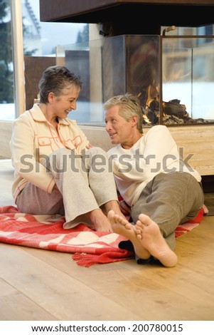 Mature couple sitting on blanket in front of fireplace